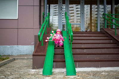 Toddler drags a toy stroller along the ramp of the stairs