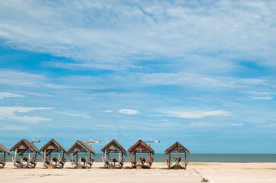 Small wooden beach shelters line on seafront. bright day with blue sky and white clouds.