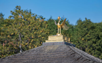 Close-up view of golden rooftop ornament against the blue sky