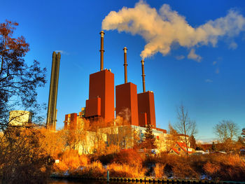 Smoke emitting from factory against sky