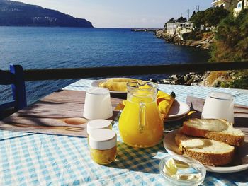 Orange juice with breakfast on table by sea