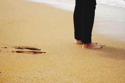 Low section of woman standing at beach