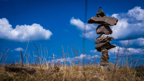Stack of rocks on field against sky