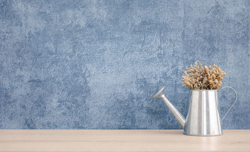 Flower vase on table against blue background