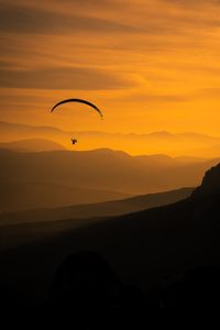 Scenic view of silhouette mountains against orange sky