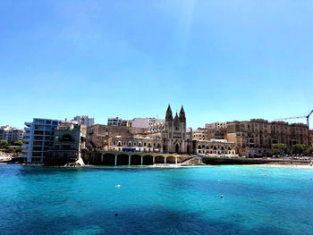 Scenic view of sea against blue sky in city