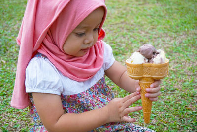 Close-up of girl holding ice cream on field