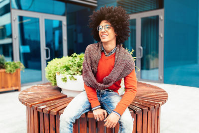 Smiling young man sitting outside building