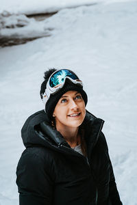 Smiling young woman looking up during winter