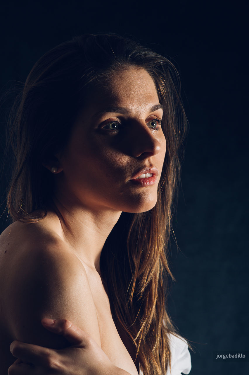 PORTRAIT OF YOUNG WOMAN WITH BLACK HAIR AGAINST GRAY BACKGROUND