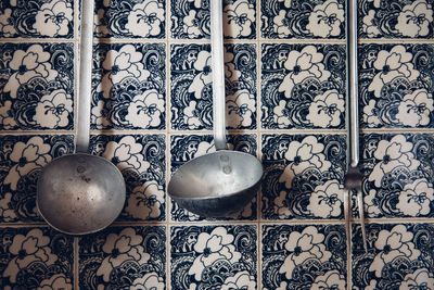 Close-up of ladles hanging against tiled wall