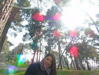 Young woman with umbrella against trees