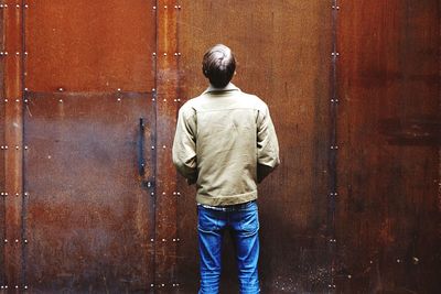 Rear view of woman standing by wall