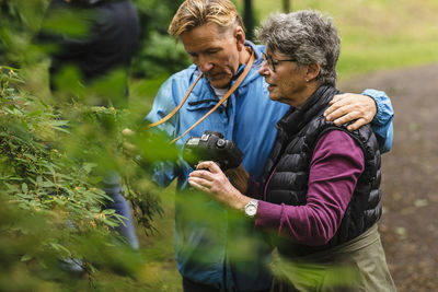 Senior woman showing camera to male friend during photography course