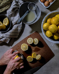 Cropped hands with lemons at table