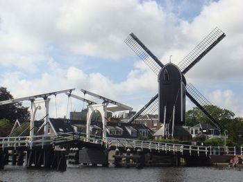 Cranes by bridge against sky