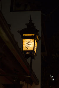 Low angle view of illuminated lanterns hanging on building wall