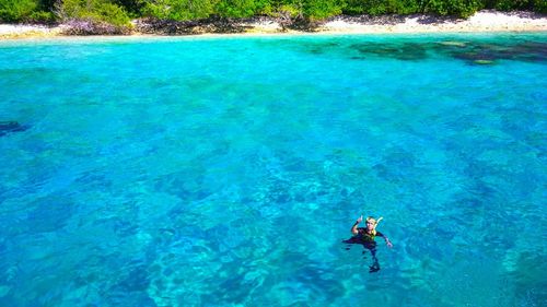 High angle view of man gesturing thumbs up while swimming in sea