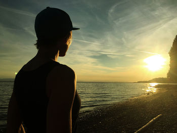 Silhouette man looking at sea against sky during sunset