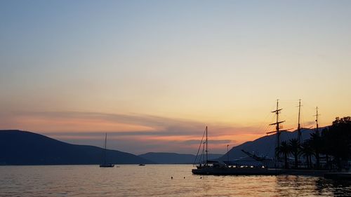 Silhouette sailboats in sea against sky during sunset