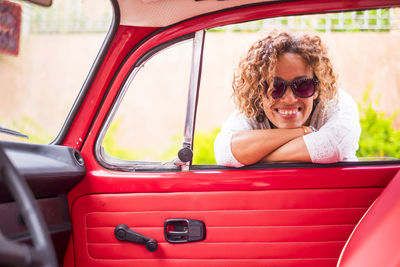 Portrait of smiling woman leaning on car door