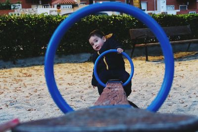 Cute boy sitting on seesaw at playground in park