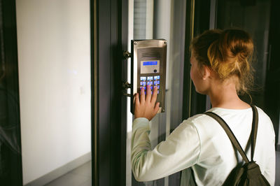 Side view of young woman using intercom