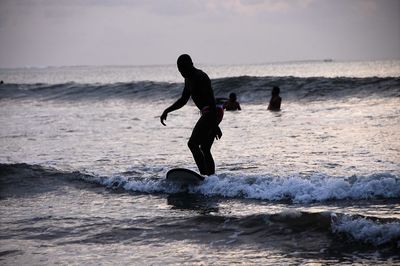 Silhouette surfer surfing against sky during sunset