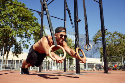 Low angle view of man swinging at playground