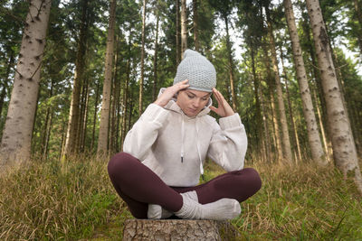 Woman sitting in a forest with her head in her hands, clearing her head of negative emotions