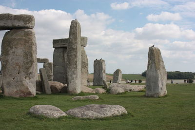 Stone structure in field against cloudy sky