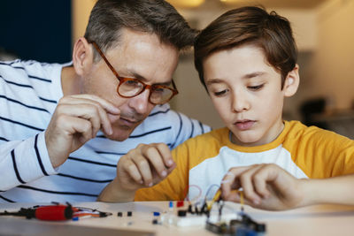 Father and son assembling an electronic construction kit