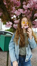 Portrait of beautiful young woman standing against flower tree