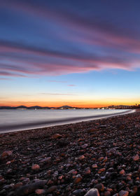 Surface level of beach against sky during sunset