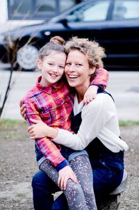 Portrait of cheerful girl embracing grandmother on footpath