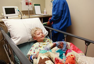 Midsection of doctor examining boy lying on bed