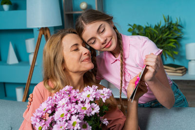 Smiling mother and daughter looking at greeting card