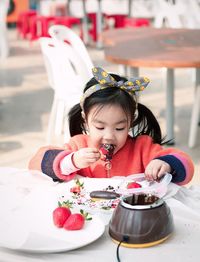 Girl eating chocolate covered strawberry at table