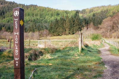 Road sign on field against sky