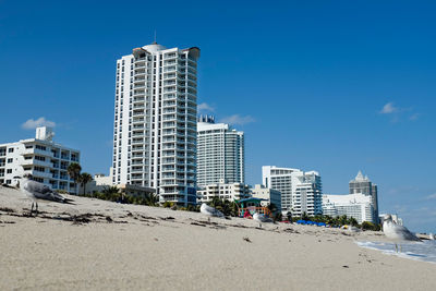 Modern buildings by sea against sky in city