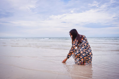 Woman with umbrella at beach against sky