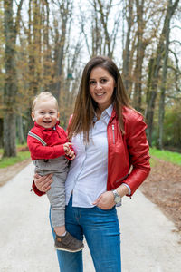 Portrait of a smiling young mother and child against trees