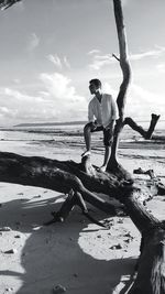 Full length of young man standing on driftwood at beach