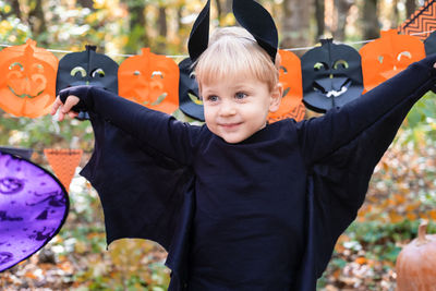 Happy boy kid in halloween costume having fun in halloween decorations outdoor