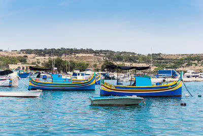 Boats moored on lake against blue sky