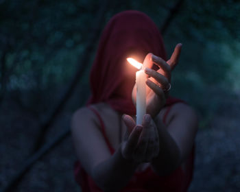 Close-up of hand holding lit candle