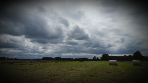 Scenic view of grassy field against cloudy sky