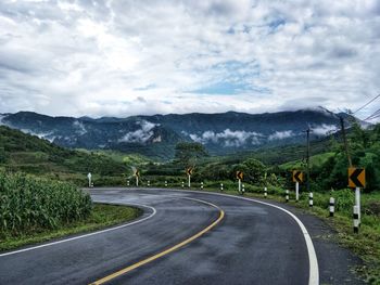 Road leading towards mountains against sky