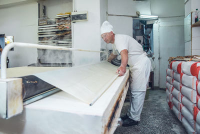 Man rolling and steaming dough at a bakery in belgrade, serbia