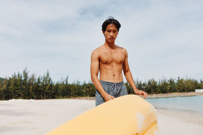 Portrait of shirtless man sitting on beach